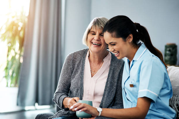 Shot of a young nurse chatting with a senior woman at home